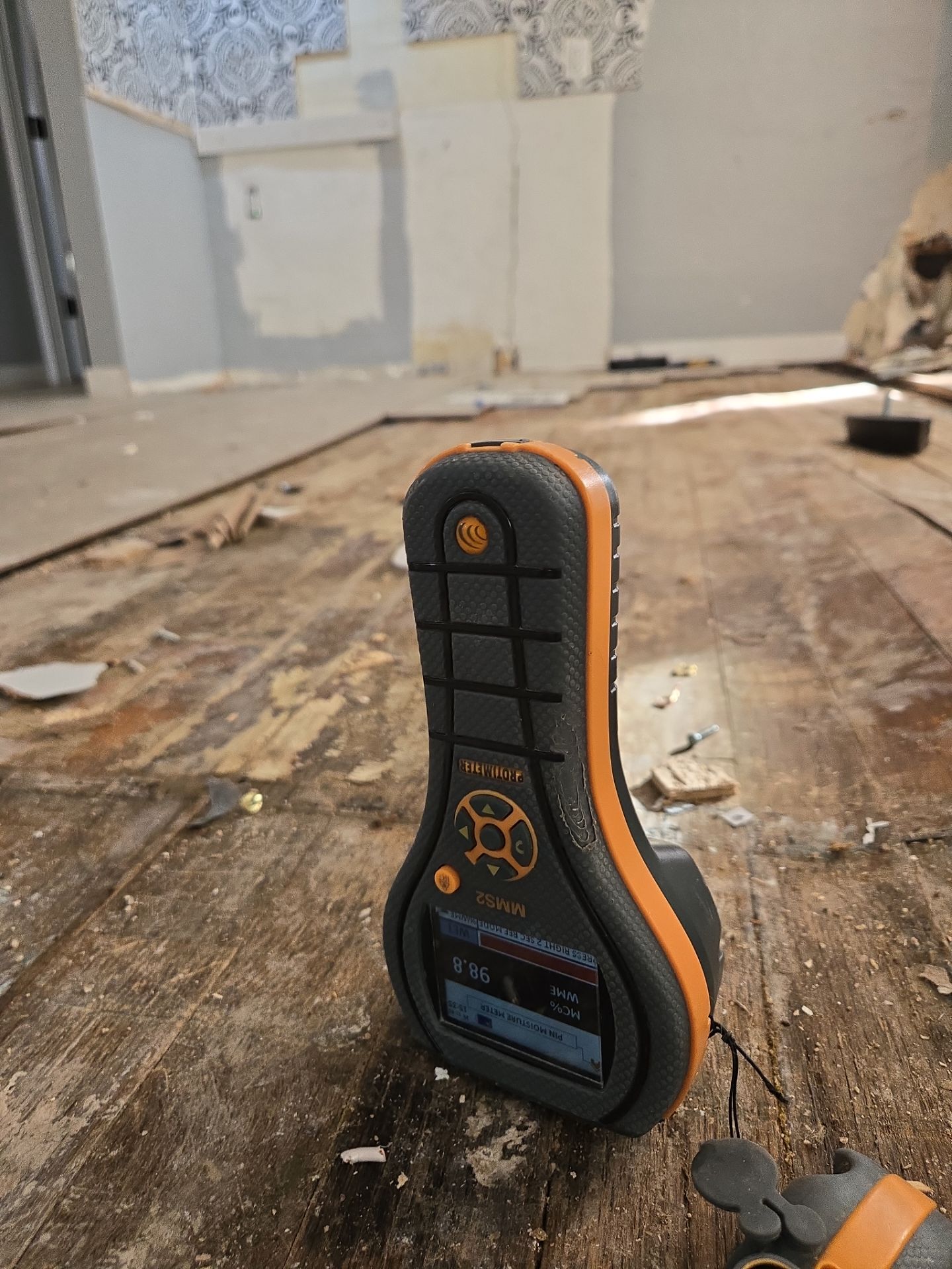 Moisture meter measuring water damage on a wooden floor