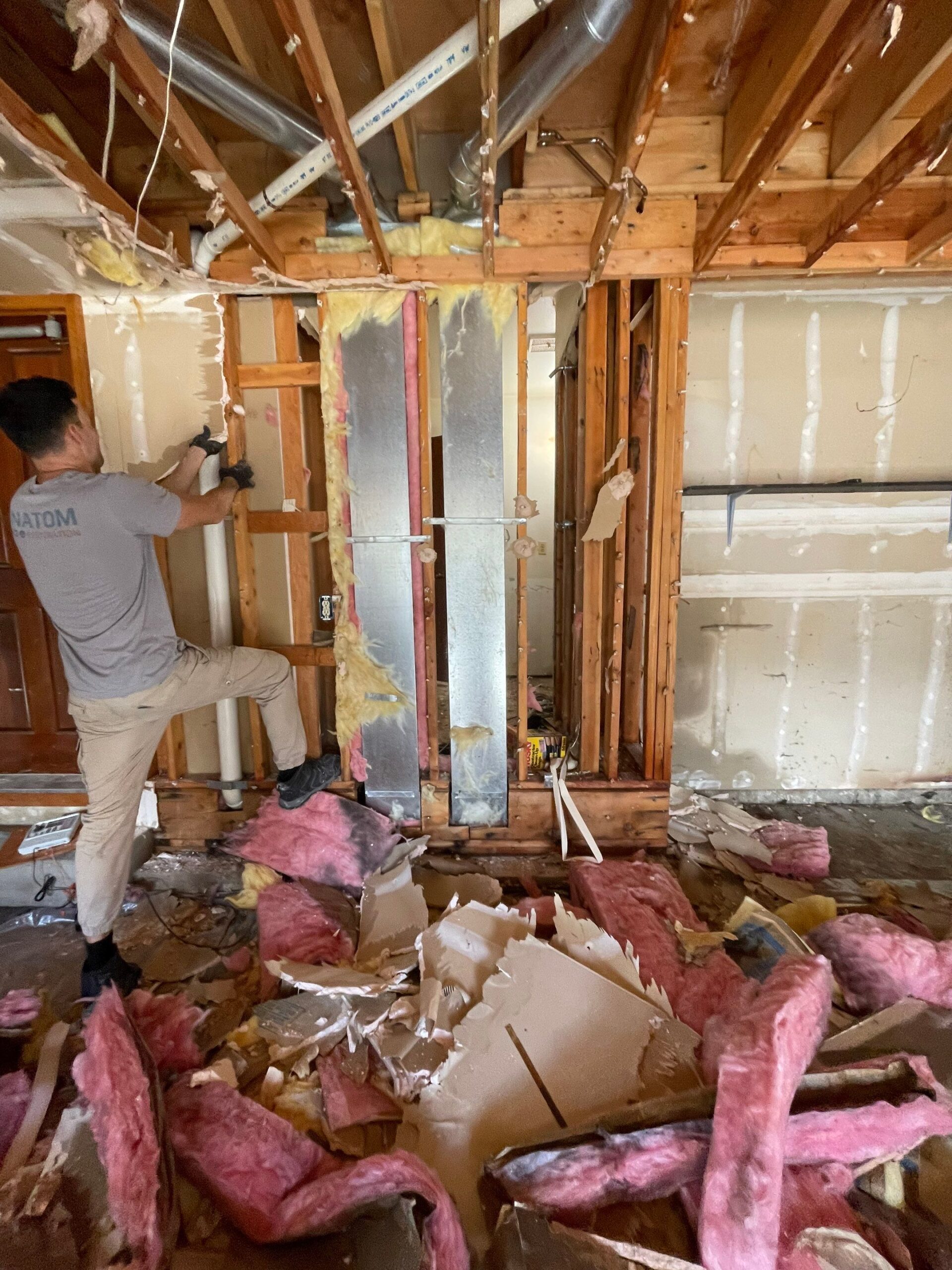 Technician performing demolition for water damage restoration.
