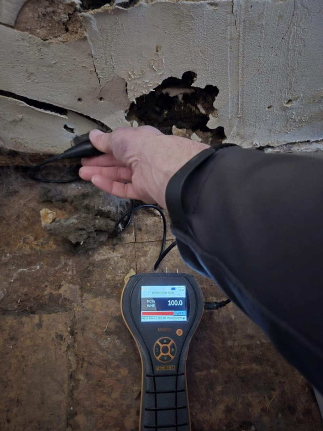 Moisture meter detecting water damage in a wall