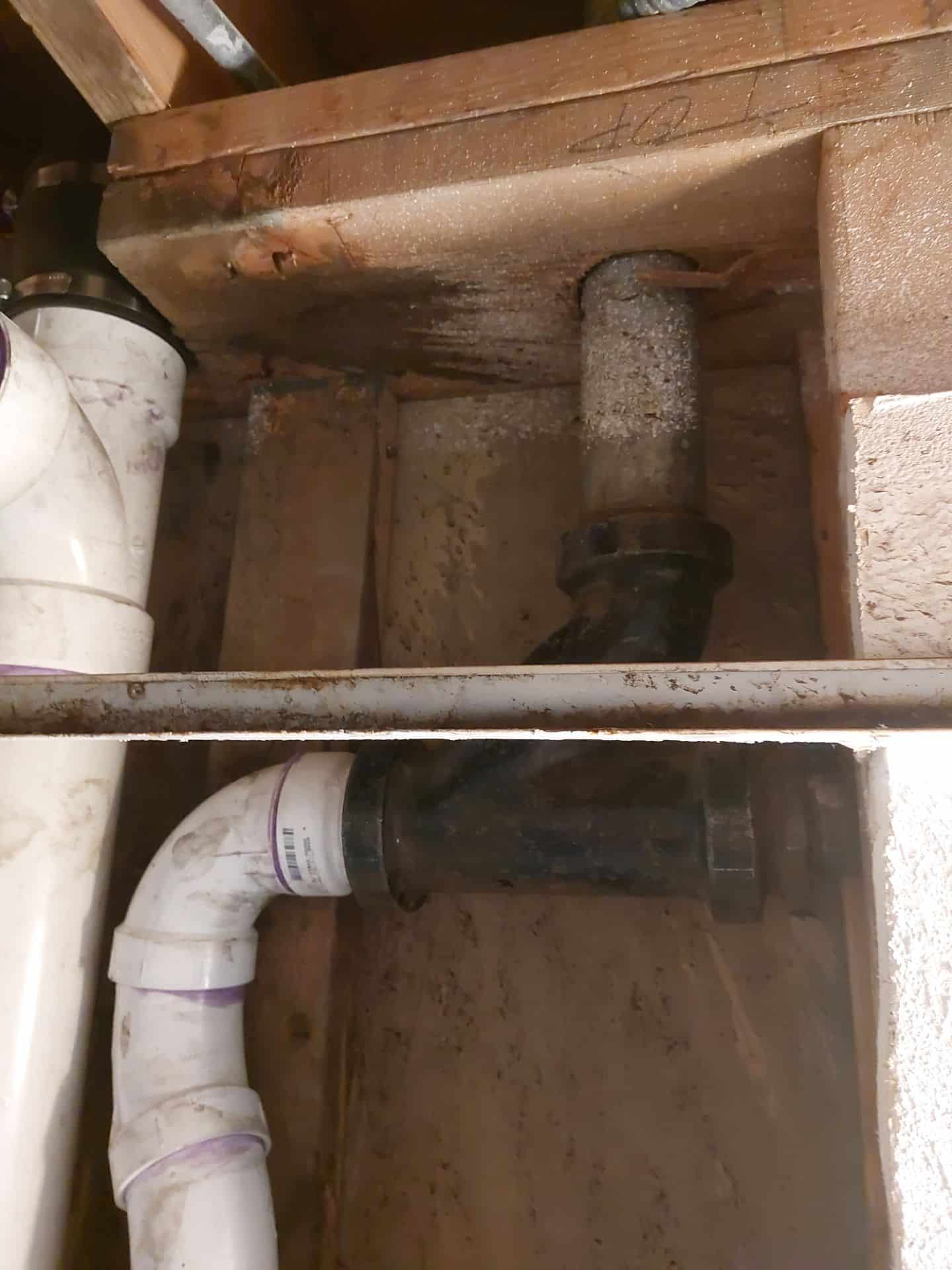 Exposed plumbing with visible pipes and signs of moisture damage