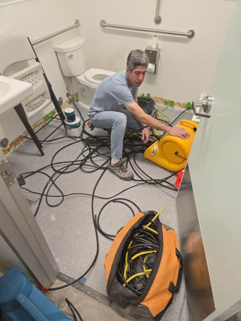 Bathroom with water damage restoration equipment and exposed flooring