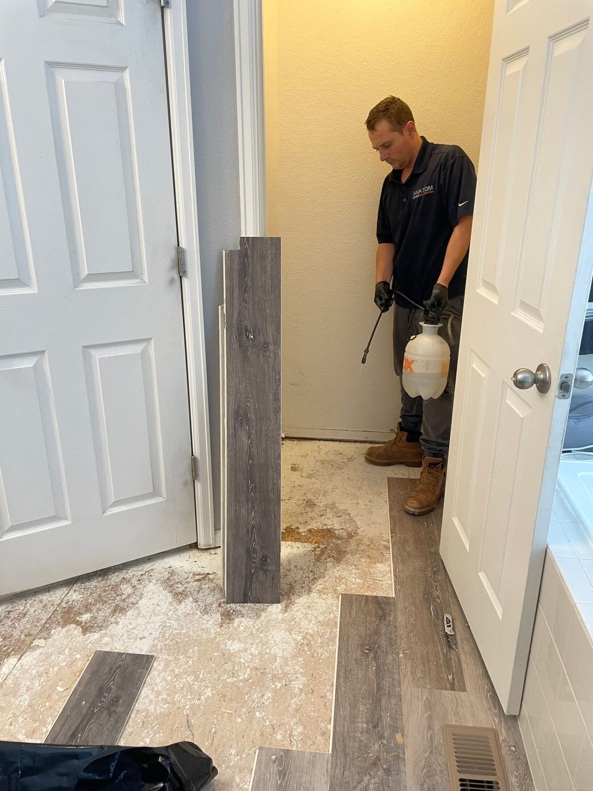 Technician treating water-damaged flooring before installing new planks.