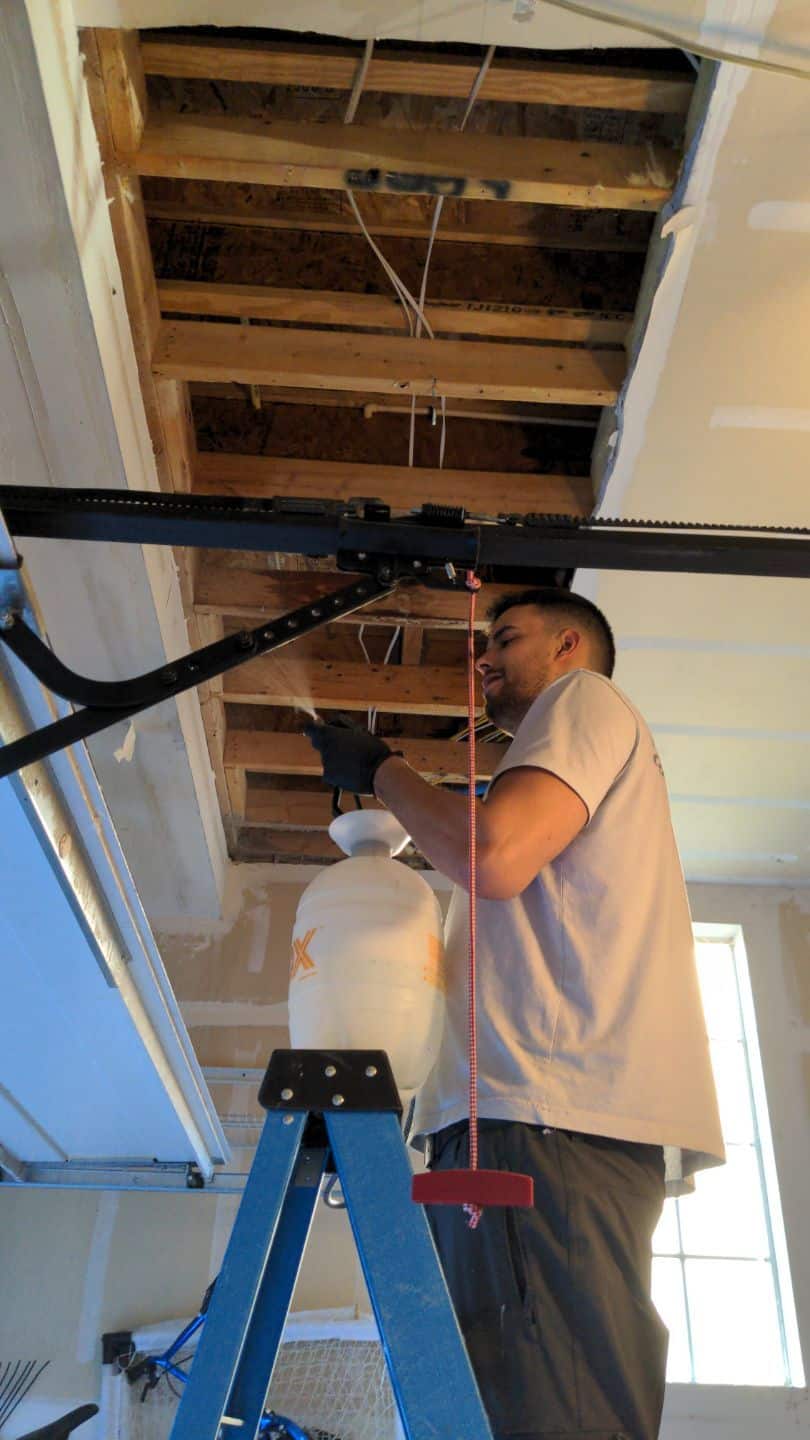 Technician treating a water-damaged ceiling with antimicrobial spray.