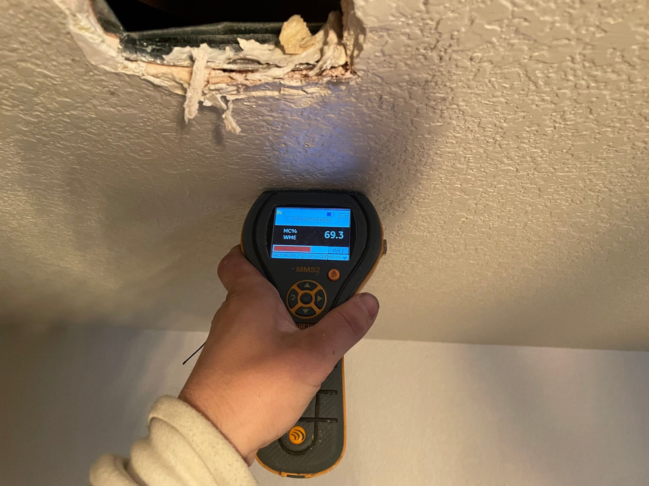 Moisture meter detecting water damage in a ceiling.