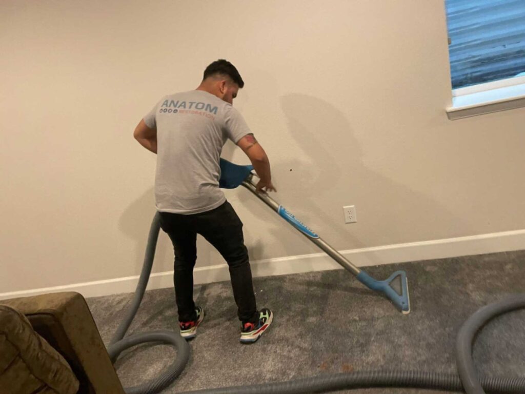 Technician extracting water from a wet carpet after flooding