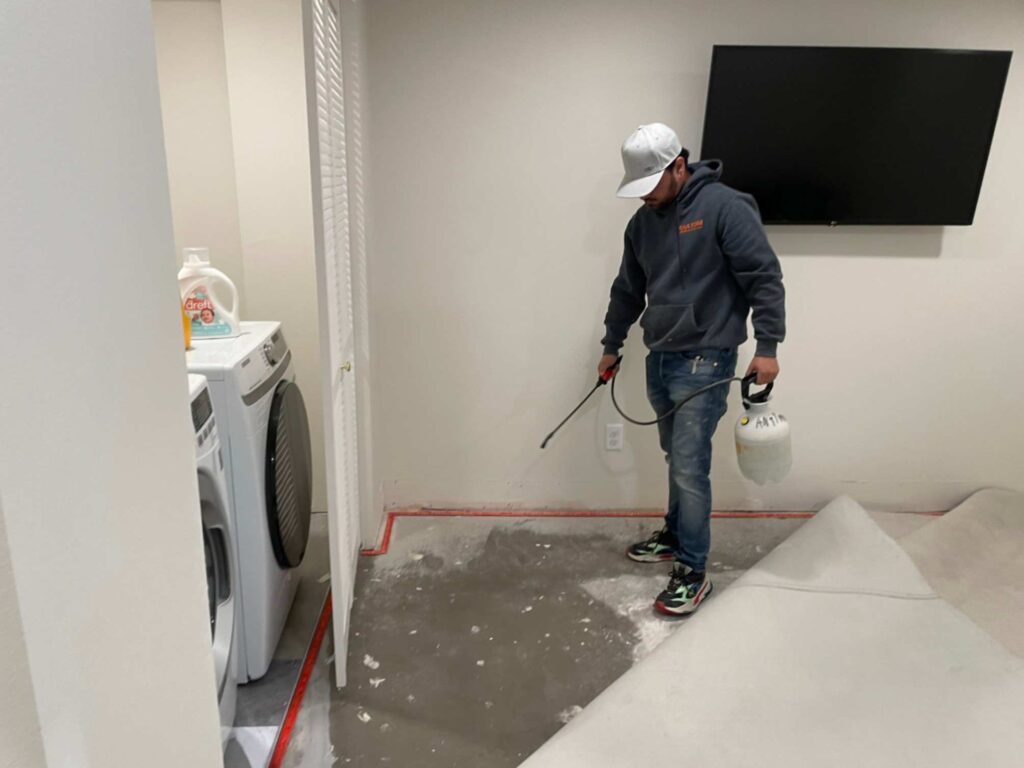 Technician treating water-damaged flooring in a laundry room