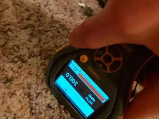 A technician using a moisture detection device on a carpeted floor