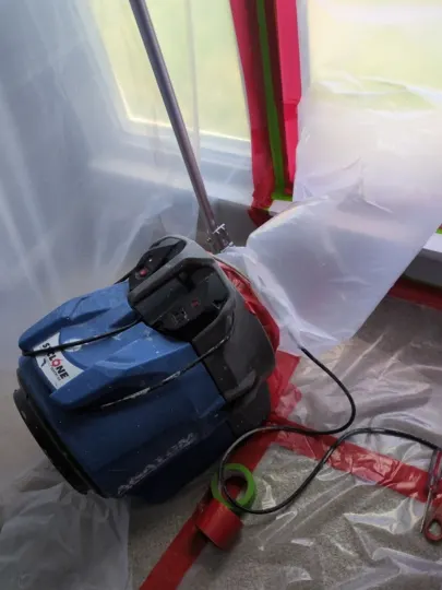 Air filtration in plastic-sealed room near window.