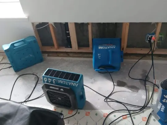 Three blue air movers are positioned in a room with a white wall and exposed wooden beams