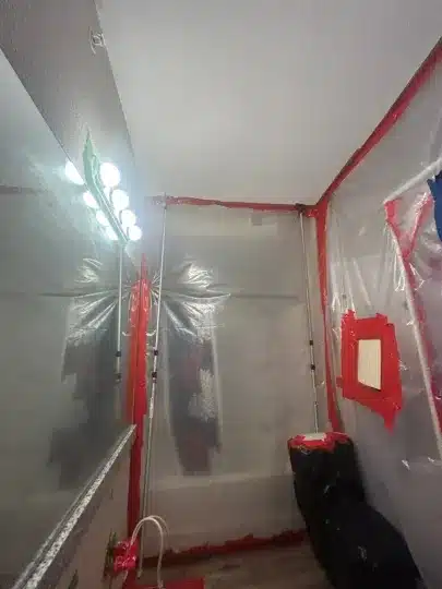 Bathroom enclosed in plastic sheeting with red tape.