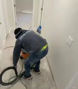 Horacio, our Mitigation Technician, uses a shop vac to clean a carpeted area during water damage restoration at a residential site