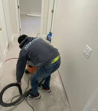 Horacio, our Mitigation Technician, uses a shop vac to clean a carpeted area during water damage restoration at a residential site