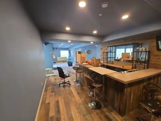 Basement bar area with partially completed flooring and tools scattered during renovation.