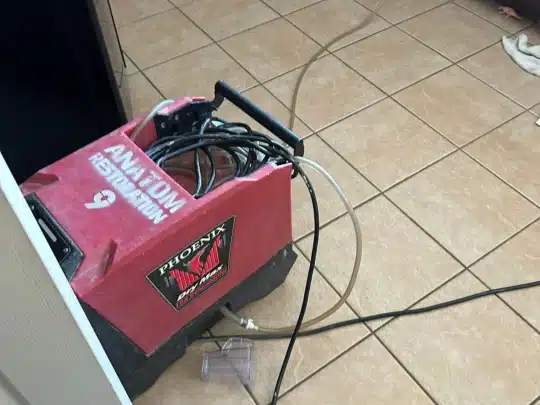 Water extraction machine placed on a tiled floor with attached hoses
