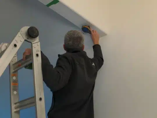 Technician measuring ceiling moisture