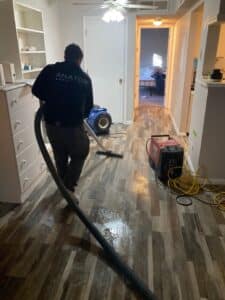 Water damage restoration technician extracting water from flooring inside a Denver home